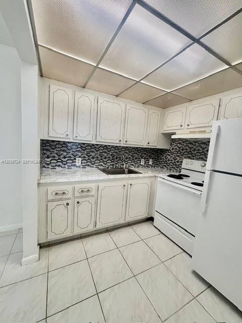 A kitchen featuring white cabinets, a mosaic tile backsplash, and a white stove — 202 Mansfield, Boca Raton FL 33434, BOCA RATON, FL