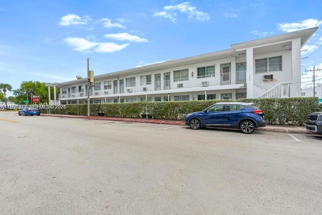 A two-story white apartment building stands behind a hedge with cars parked in front — 200 76th St # 59, Miami Beach FL 33141, MIAMI BEACH, FL