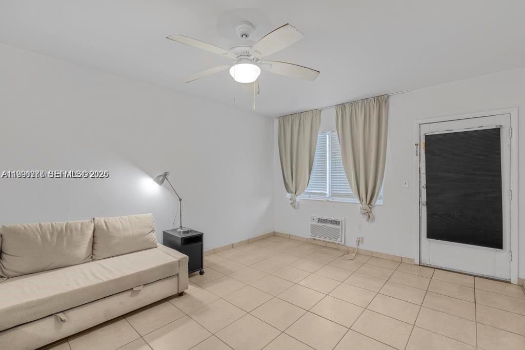 A room with a beige sofa, tile flooring, a ceiling fan, and a window with curtains — 200 76th St # 59, Miami Beach FL 33141, MIAMI BEACH, FL