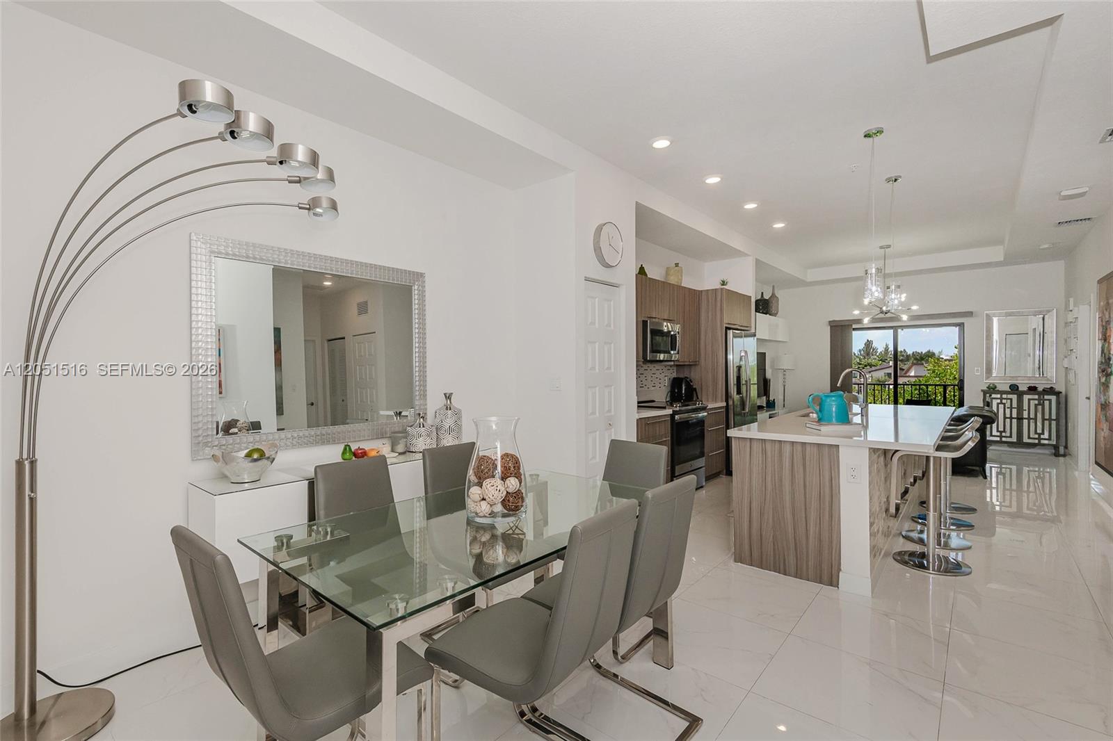 A modern dining area and kitchen feature a glass table, gray chairs, and marble floors — 7815 NW 104th Ave # 34, Doral FL 33178, DORAL, FL