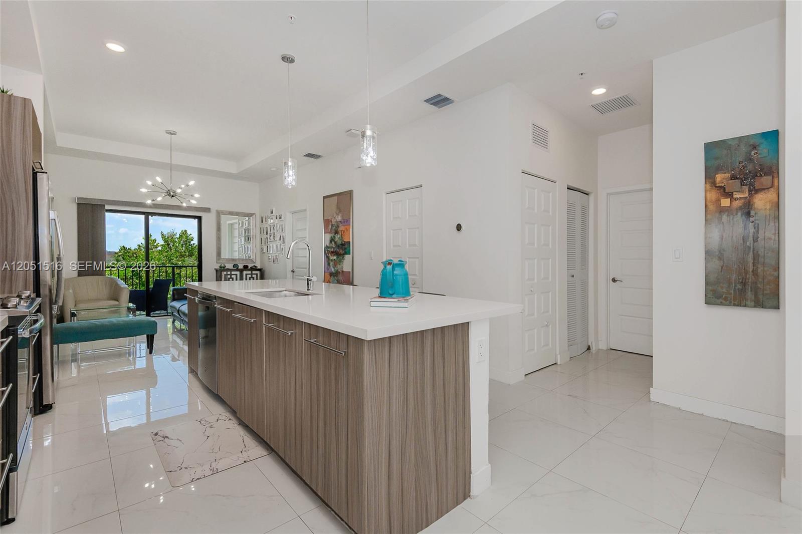 A modern kitchen features a large wood-toned island with a white countertop and tile flooring — 7815 NW 104th Ave # 34, Doral FL 33178, DORAL, FL