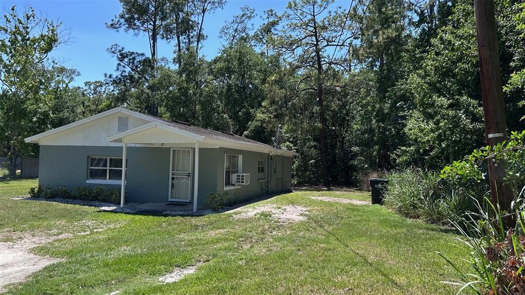 A single-story house with gray siding and a white roof sits on a grassy lot — 4800 PETROFF AVENUE, ORLANDO, FL