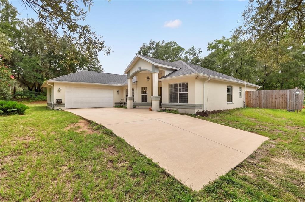 A single-story house with a beige stucco exterior, a two-car garage, and a concrete driveway — 7300 SW 204TH AVENUE, DUNNELLON, FL