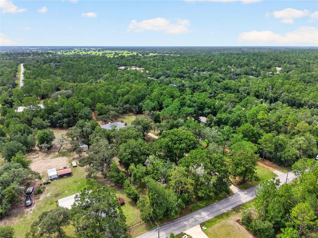 An aerial view shows a rural property with a house, outbuildings, and dense surrounding forest — 7300 SW 204TH AVENUE, DUNNELLON, FL