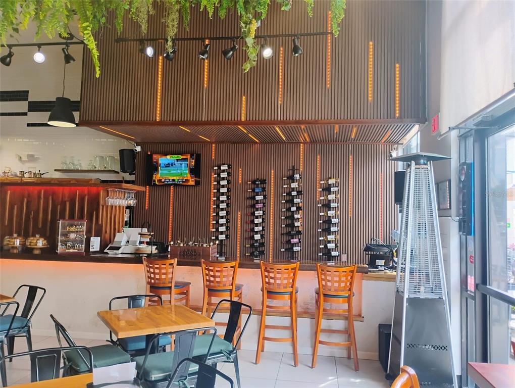 A bar area features wooden slat walls, hanging greenery, bar stools, and wall-mounted wine racks — 8001 S ORANGE BLOSSOM TRAIL, ORLANDO, FL
