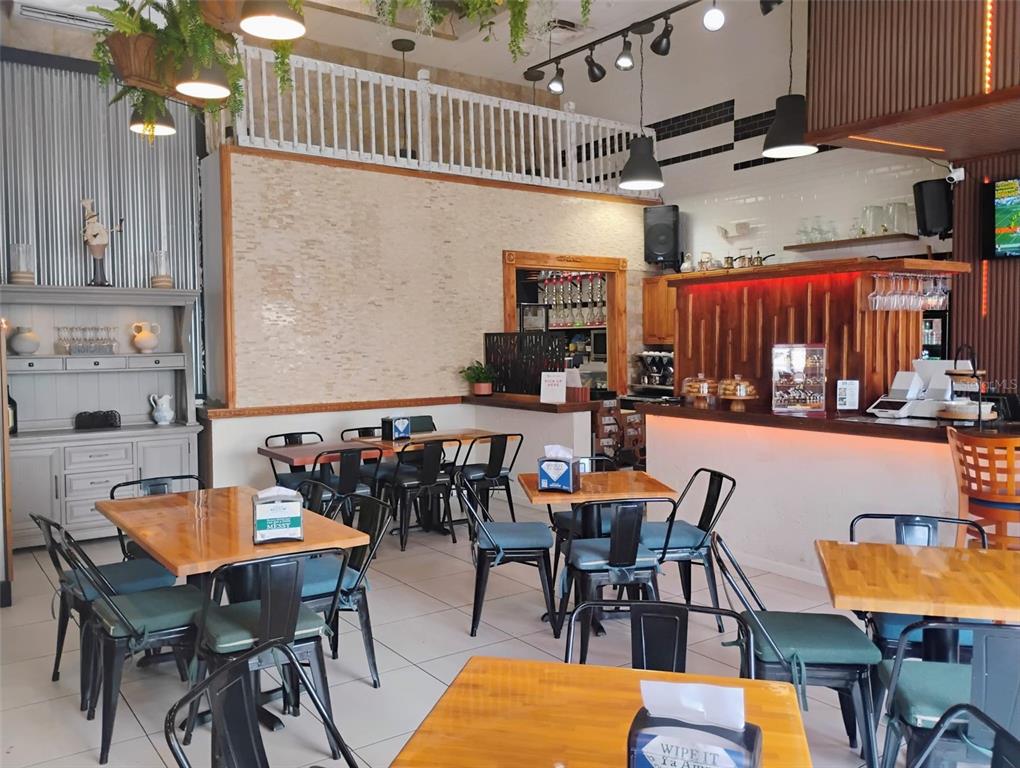 A restaurant interior features wooden tables, black metal chairs, a bar area, and decorative lighting — 8001 S ORANGE BLOSSOM TRAIL, ORLANDO, FL