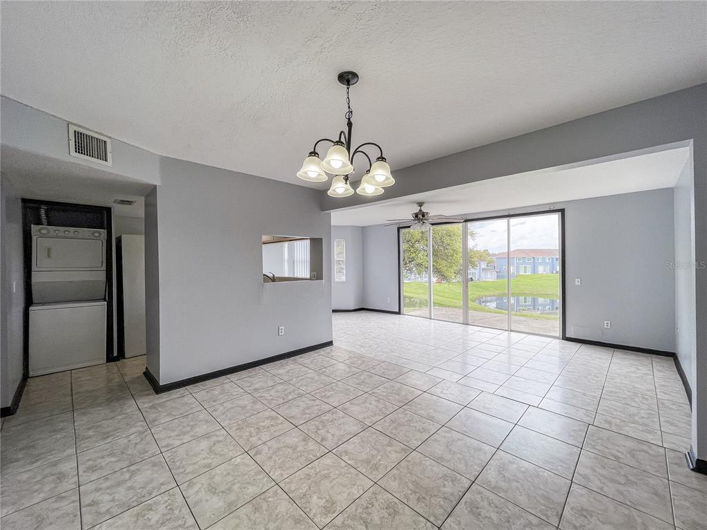 A tiled dining area features a chandelier, a laundry closet, and sliding glass doors to outdoors — 402 ORCHID DRIVE Main Unit, DAVENPORT, FL