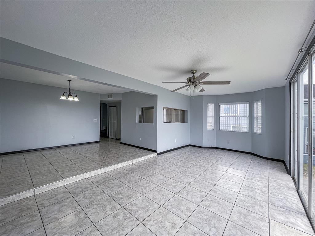 A living and dining area with light gray walls, tile flooring, and a ceiling fan — 402 ORCHID DRIVE Main Unit, DAVENPORT, FL