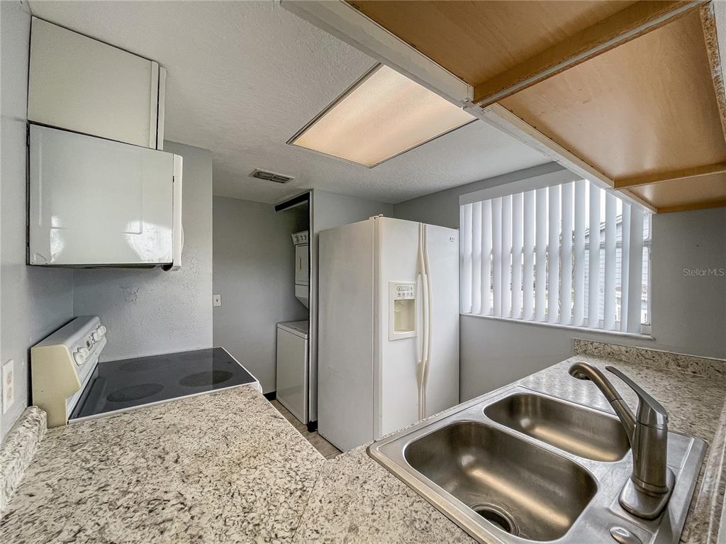 A kitchen features granite countertops, a double-basin sink, white appliances, and a laundry closet — 402 ORCHID DRIVE Main Unit, DAVENPORT, FL