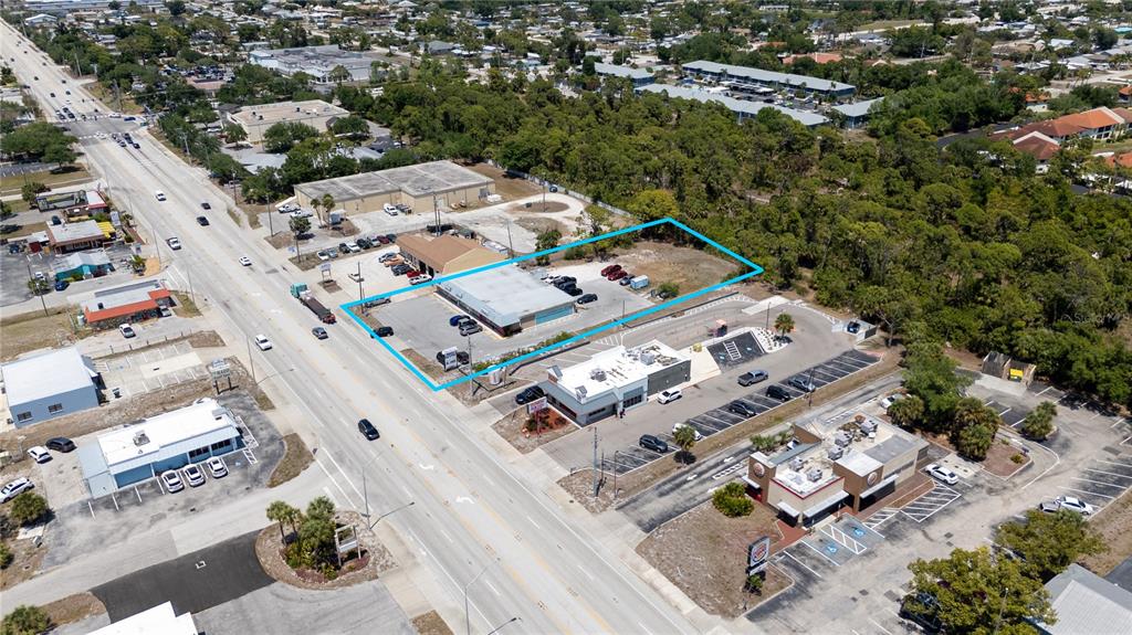 An aerial view shows a commercial building outlined in blue situated along a busy road — 119 S INDIANA AVENUE, ENGLEWOOD, FL