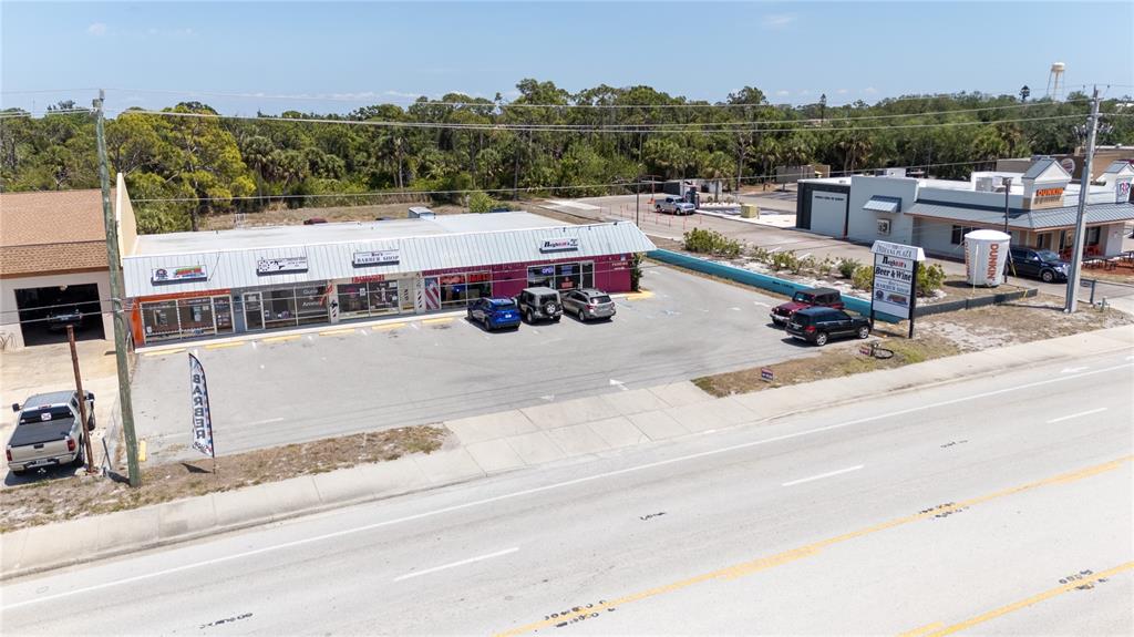 An aerial view shows a commercial strip mall with a parking lot and adjacent road — 119 S INDIANA AVENUE, ENGLEWOOD, FL