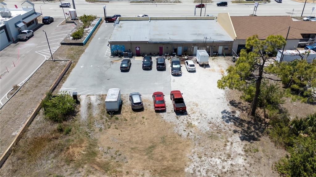 An aerial view shows a commercial building with a parking lot and adjacent vacant land — 119 S INDIANA AVENUE, ENGLEWOOD, FL