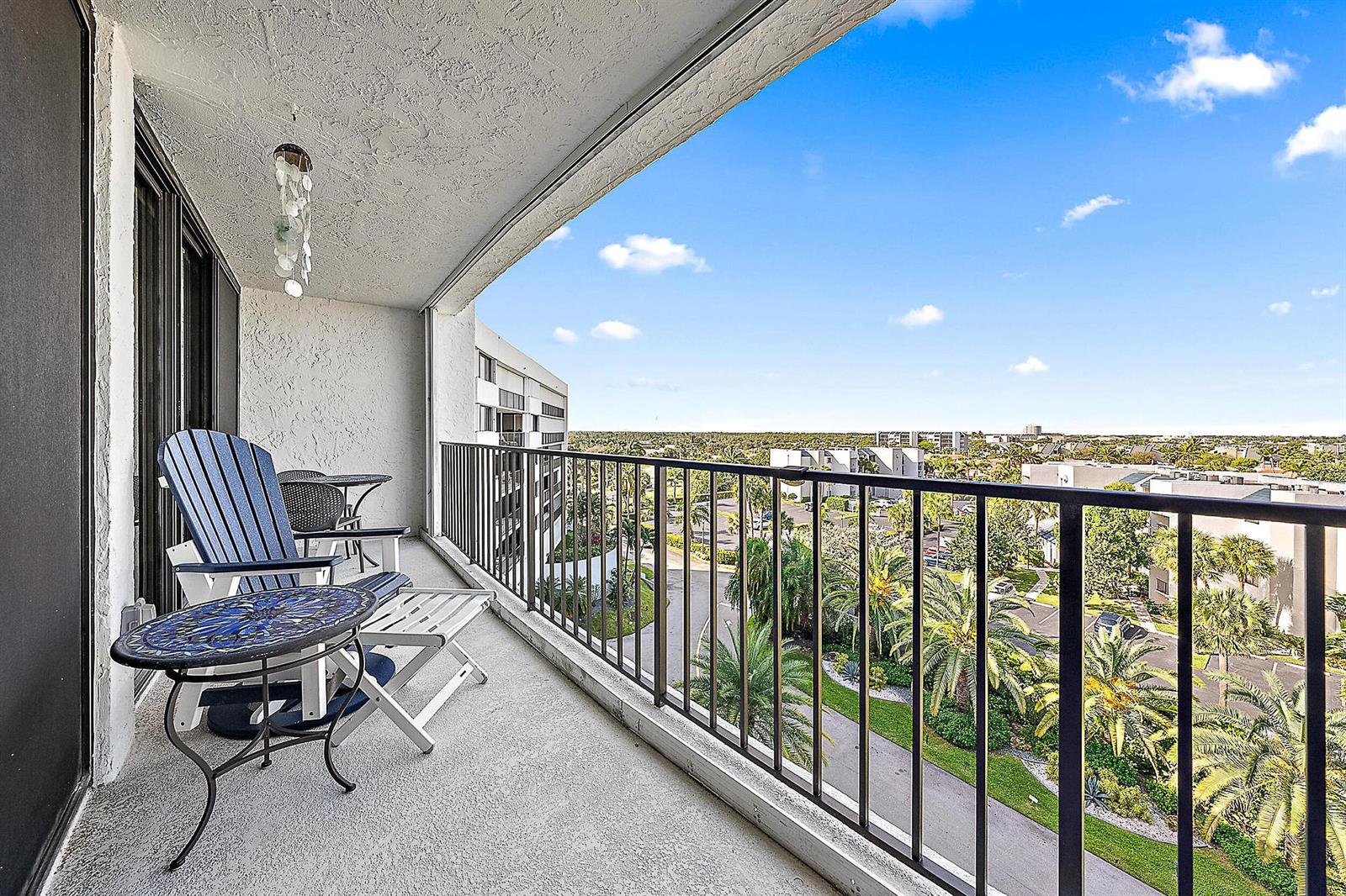 A balcony with outdoor furniture overlooks a landscaped residential area under a blue sky — 1300 S Highway A1a # 523, Jupiter FL 33477, JUPITER, FL