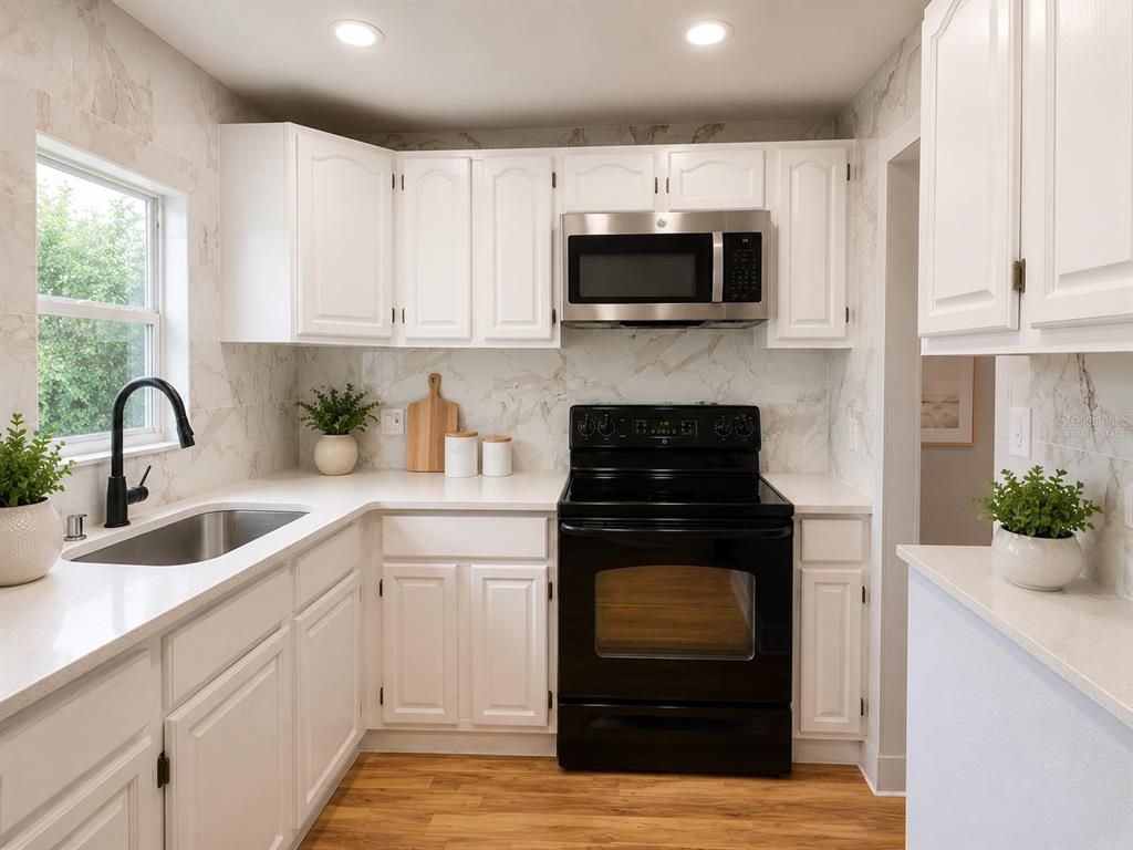 A kitchen features white cabinets, marble-patterned backsplash, stainless steel appliances, and wood-look flooring — 821 S SOLANDRA DRIVE, ORLANDO, FL