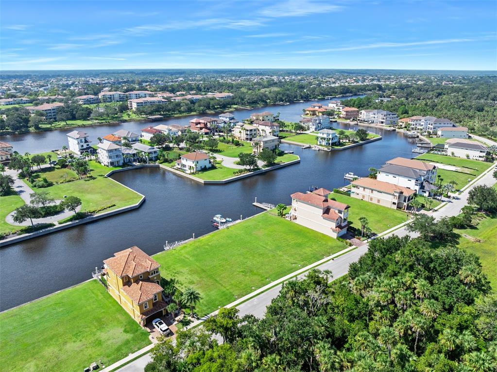 An aerial view shows waterfront houses with green lawns and boat docks along a canal — 278 HARBOR VILLAGE POINT N, PALM COAST, FL