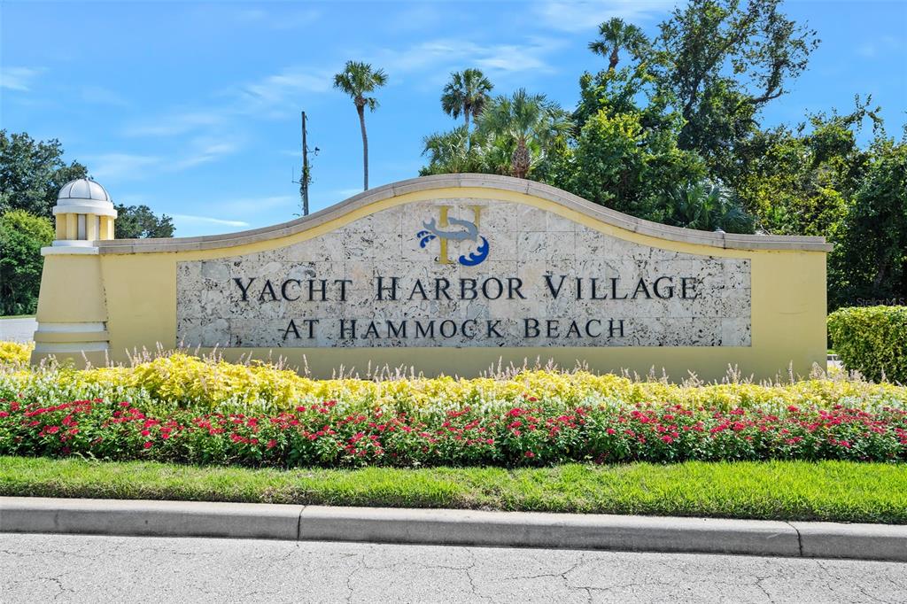 A stone monument sign for Yacht Harbor Village at Hammock Beach sits behind landscaped flowers — 278 HARBOR VILLAGE POINT N, PALM COAST, FL