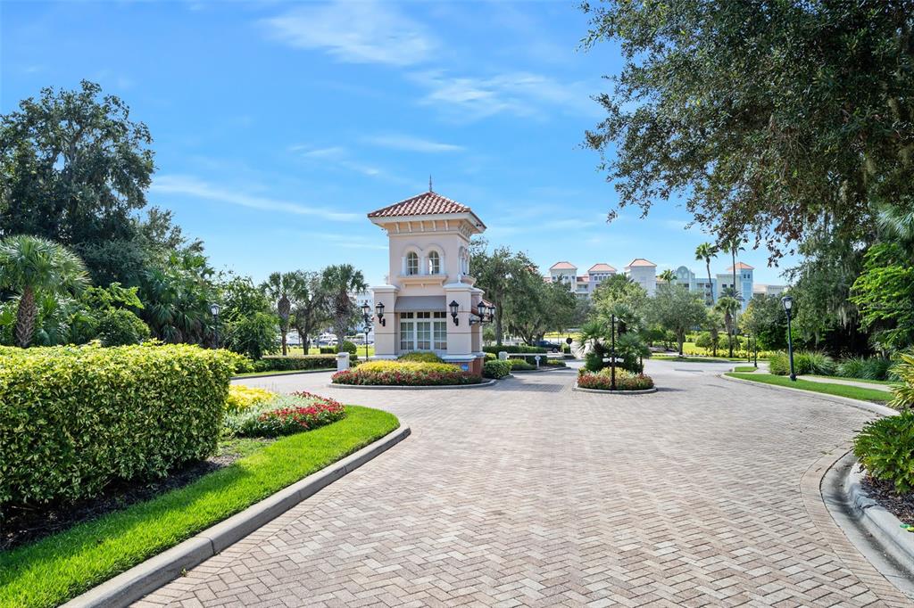 A paved driveway leads to a gated entrance structure surrounded by lush landscaping and trees — 278 HARBOR VILLAGE POINT N, PALM COAST, FL