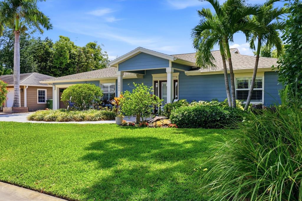 A blue single-story house features a covered entryway, palm trees, and a manicured front lawn — 1880 LOMA LINDA STREET, SARASOTA, FL