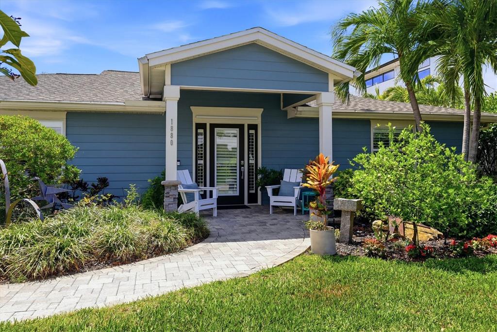 A blue house with a covered entryway, white chairs, and a stone walkway — 1880 LOMA LINDA STREET, SARASOTA, FL
