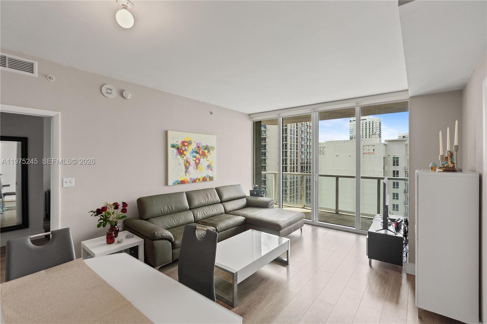 A living room features a gray sectional sofa, white coffee table, and a balcony view — 244 Biscayne Blvd # 2410, Miami FL 33132, MIAMI, FL