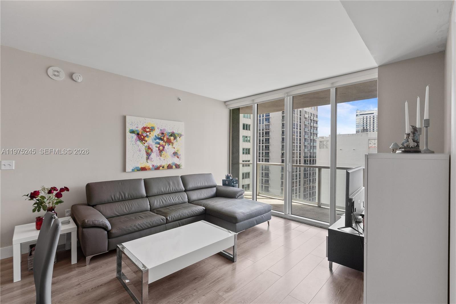 A living room features a gray sectional sofa, white coffee table, and floor-to-ceiling balcony windows — 244 Biscayne Blvd # 2410, Miami FL 33132, MIAMI, FL