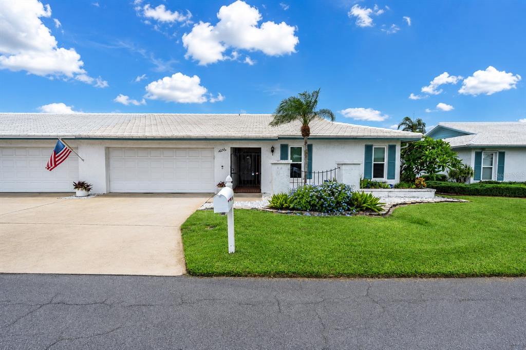A white single-story house with a two-car garage, a palm tree, and a green lawn — 7315 8TH AVENUE W UNIT 5824, BRADENTON, FL