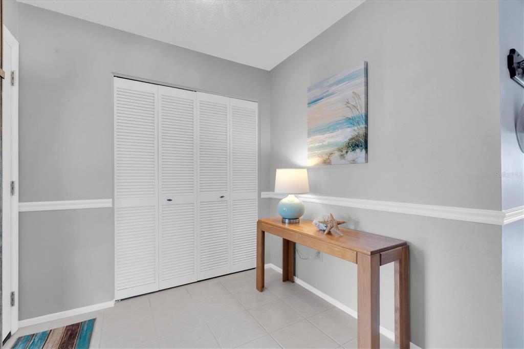 A hallway features light gray walls, white louvered closet doors, and a wooden console table — 7315 8TH AVENUE W UNIT 5824, BRADENTON, FL