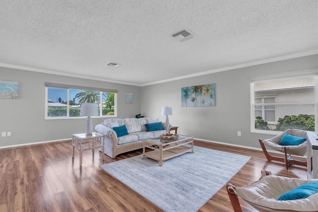 A living room features light gray walls, wood-look flooring, a sofa, and two accent chairs — 7315 8TH AVENUE W UNIT 5824, BRADENTON, FL