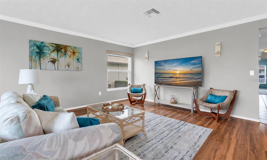 A living room features a sofa, two accent chairs, a glass coffee table, and television — 7315 8TH AVENUE W UNIT 5824, BRADENTON, FL