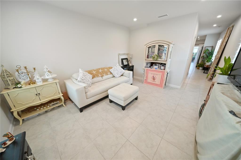 A living room features a white sofa, ottoman, and a light-colored console table on tile — 4175 HARBOUR PALM DRIVE, HOLIDAY, FL