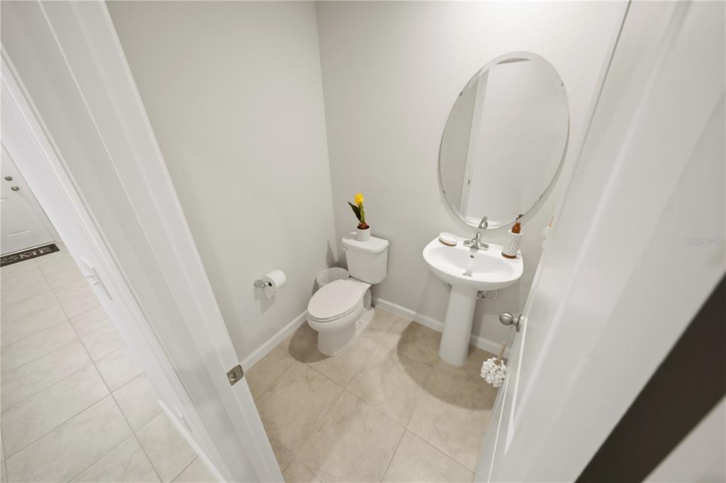 A small powder room features a pedestal sink, an oval mirror, and a toilet — 4175 HARBOUR PALM DRIVE, HOLIDAY, FL