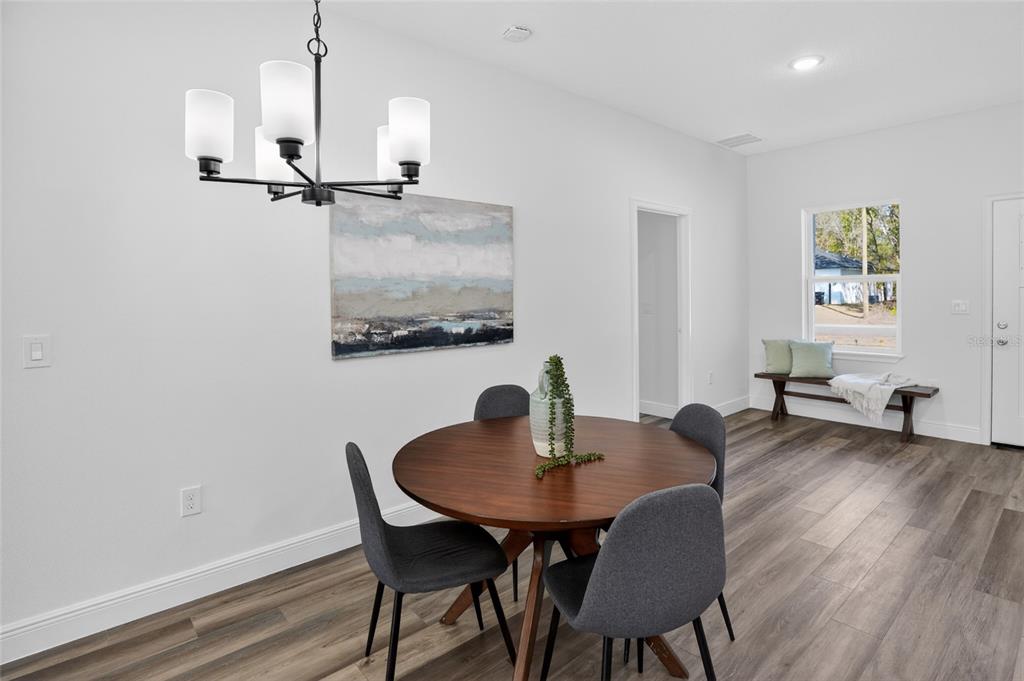 A dining room features a round wooden table, four gray chairs, and a modern chandelier — 8125 N MALTESE DRIVE, CITRUS SPRINGS, FL