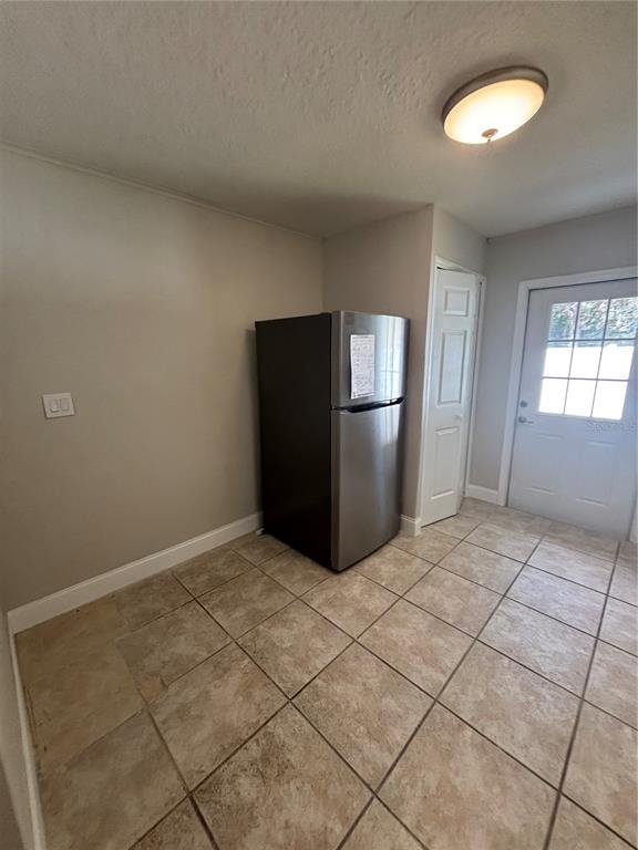 A stainless steel refrigerator stands in a tiled room with a door and ceiling light — 1224 S GRAND HIGHWAY, CLERMONT, FL