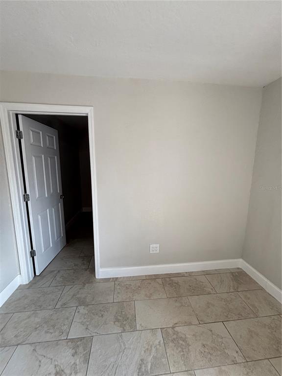A room with light gray walls, tile flooring, and an open doorway leading to a hallway — 1224 S GRAND HIGHWAY, CLERMONT, FL