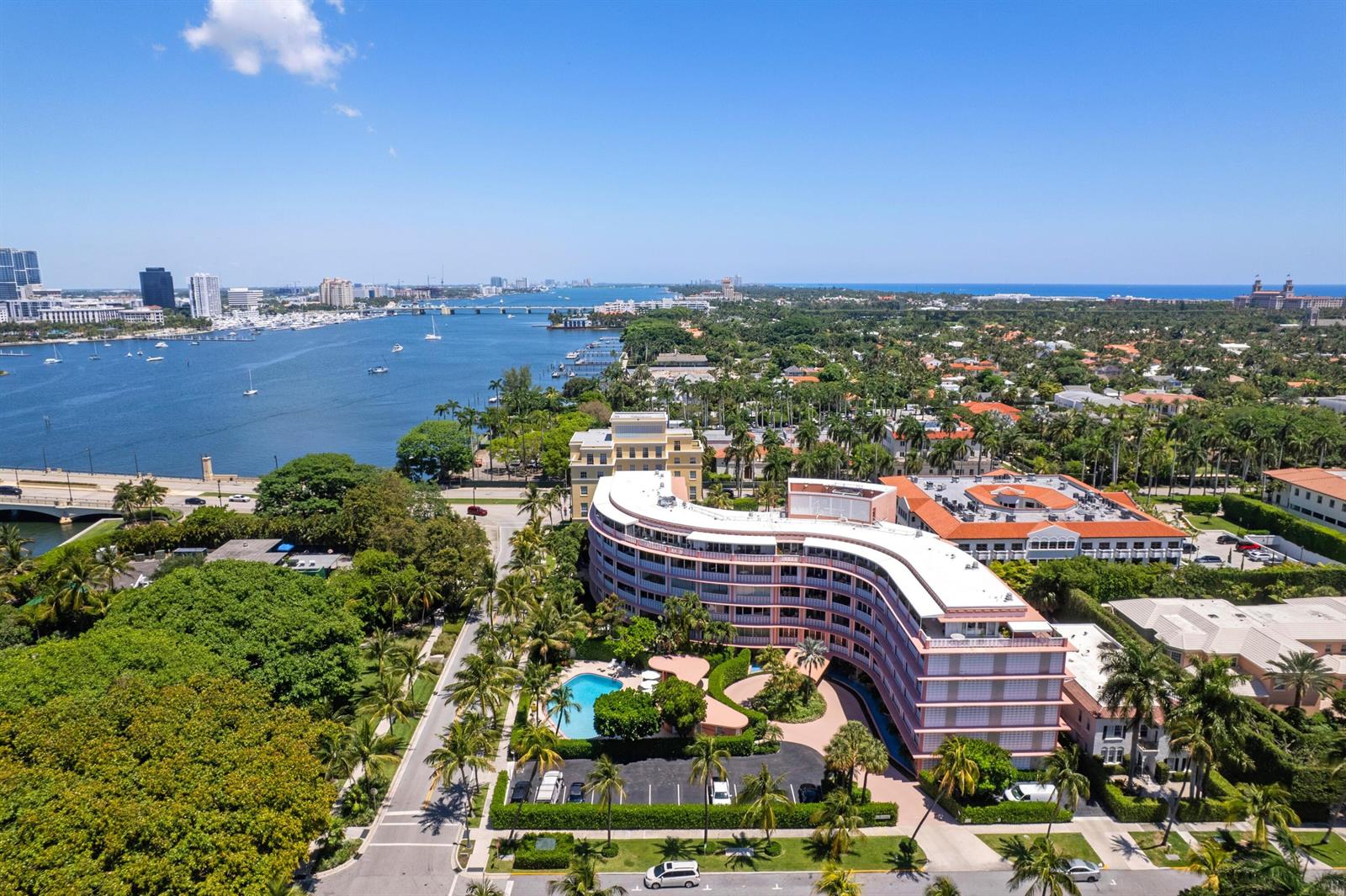 An aerial view shows a curved pink apartment building with a pool near a waterway — 315 S Lake Drive # 1a, Palm Beach FL 33480, PALM BEACH, FL