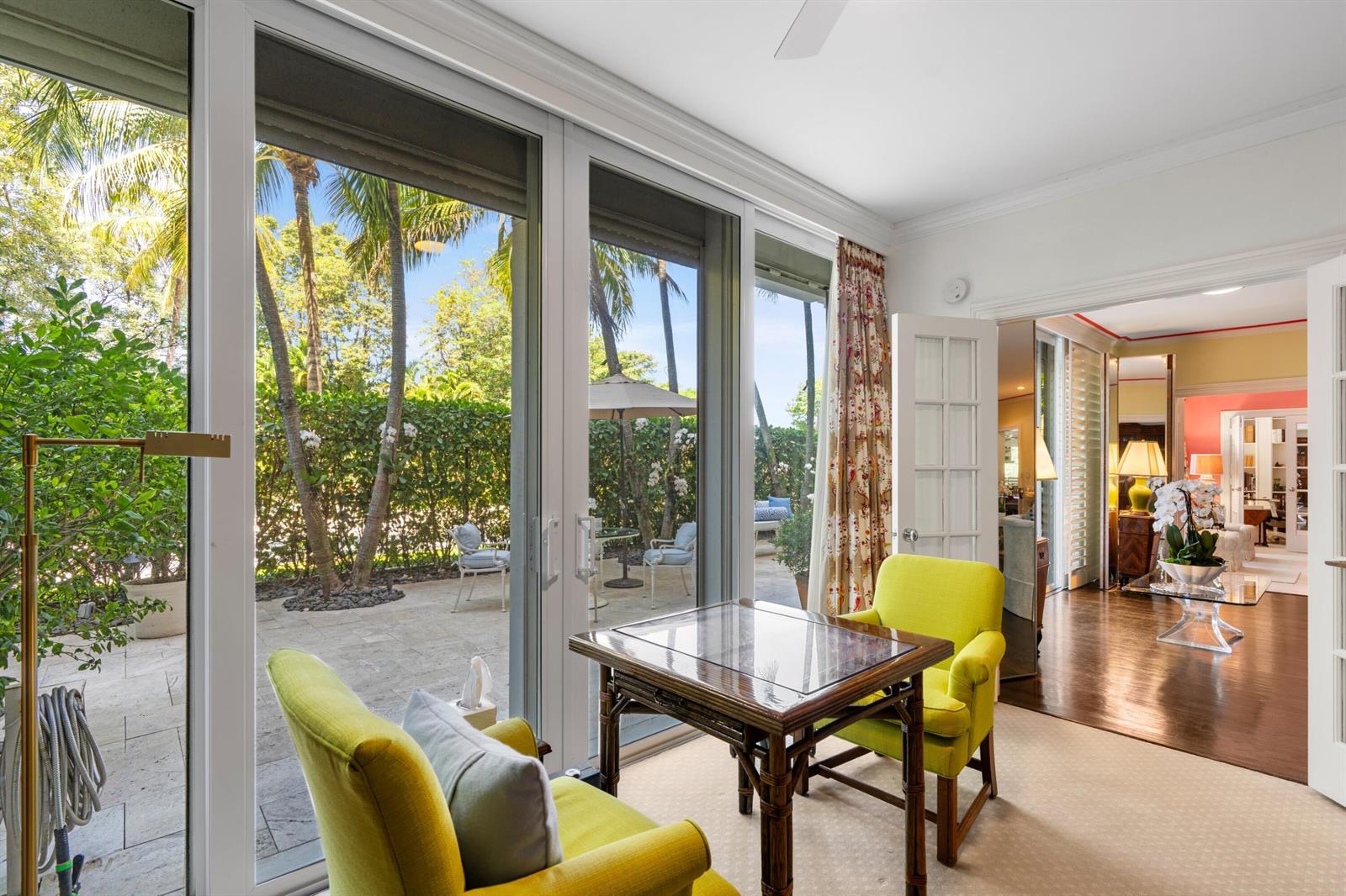 A sunroom features two lime green chairs, a wooden table, and sliding doors to a patio — 315 S Lake Drive # 1a, Palm Beach FL 33480, PALM BEACH, FL