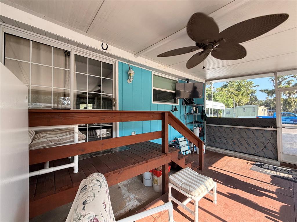 A covered patio features a wooden deck, a ceiling fan, and a blue exterior wall — 56350 ACORN ROAD, ASTOR, FL
