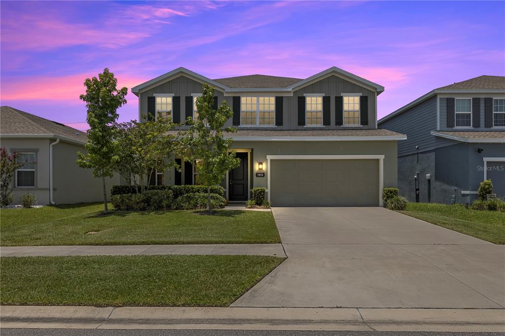 A two-story suburban house features a two-car garage and a green exterior with shutters — 7878 GREENWAY AVENUE, WESLEY CHAPEL, FL
