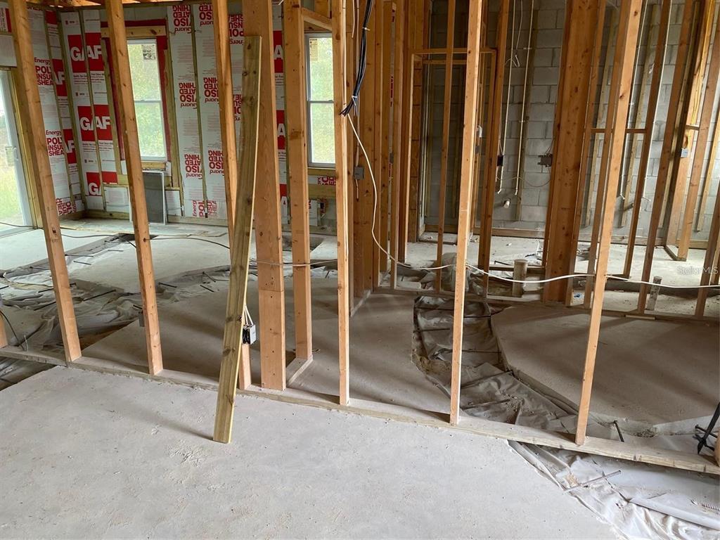 An interior view of a house under construction featuring exposed wood framing and concrete floors — 339 CAMELLIA COURT, KISSIMMEE, FL