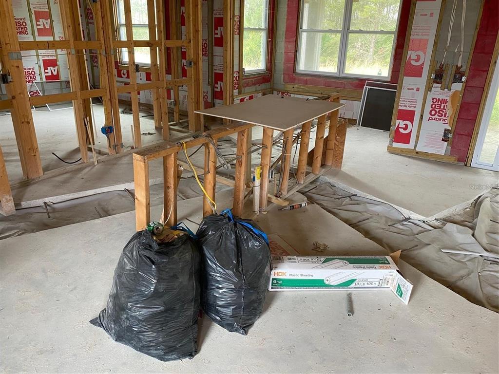 An interior view of a room under construction with exposed wood framing and concrete floors — 339 CAMELLIA COURT, KISSIMMEE, FL