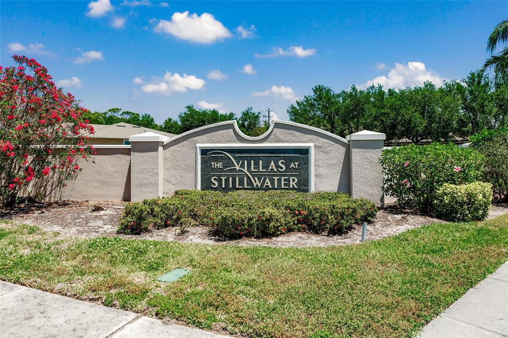 A stone monument sign for The Villas at Stillwater stands in a landscaped yard — 29696 ONTARIO COURT, ENGLEWOOD, FL