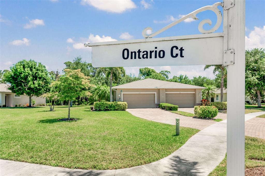 A street sign for Ontario Ct stands in the foreground of a suburban house exterior — 29696 ONTARIO COURT, ENGLEWOOD, FL