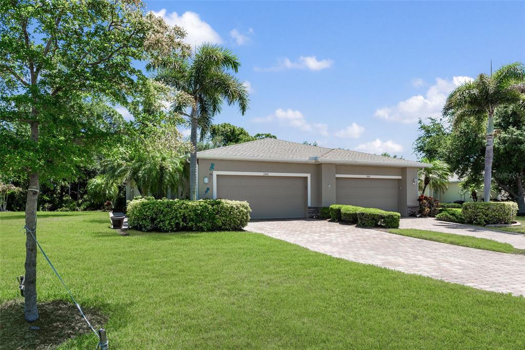A single-story house with a two-car garage and a paved driveway sits on a lawn — 29696 ONTARIO COURT, ENGLEWOOD, FL