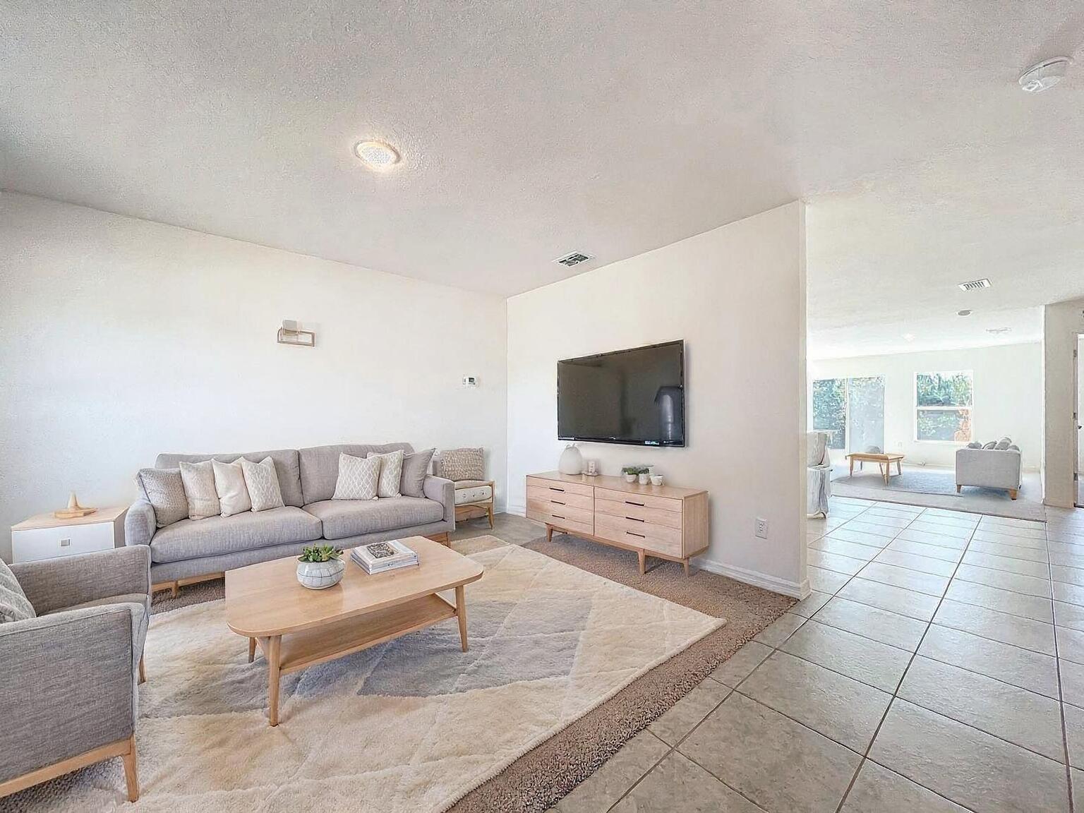 A living room features a grey sofa, a wooden coffee table, and a wall-mounted television — 1390 Schumann Drive, Sebastian FL 32958, SEBASTIAN, FL