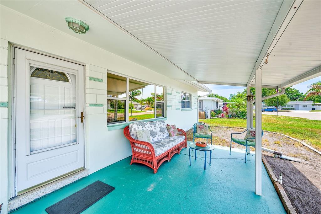 A covered patio features a teal floor, a wicker sofa, two chairs, and a small table — 3255 57TH STREET N, ST PETERSBURG, FL