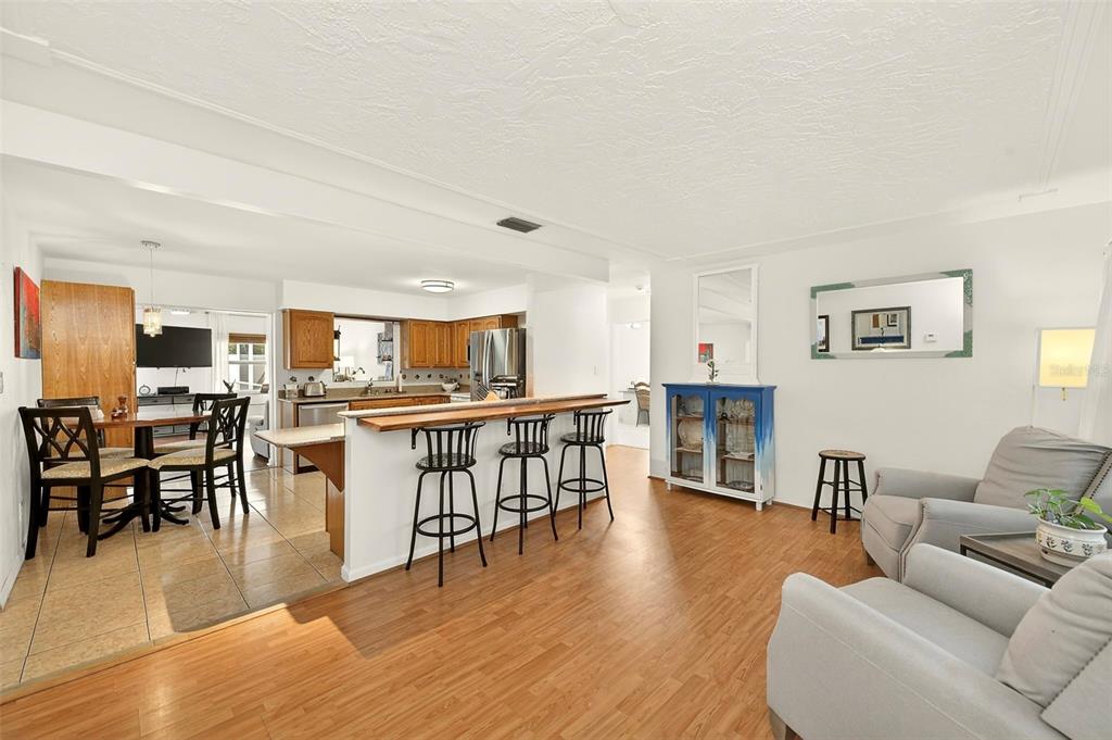 An open-concept living and dining area features wood-look flooring, a breakfast bar, and kitchen cabinetry — 3255 57TH STREET N, ST PETERSBURG, FL