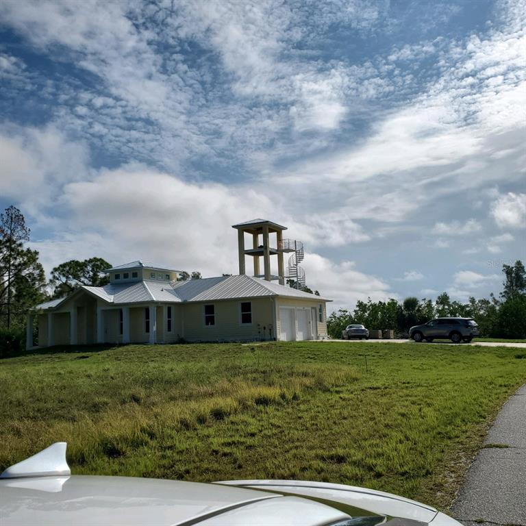 A light-colored house with a metal roof and a detached observation tower with a spiral staircase — 16285 RENNIE ROAD, PORT CHARLOTTE, FL