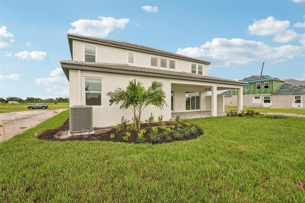 The rear exterior of a two-story house features a covered patio and a landscaped yard — 7660 SEAHAWK AVENUE, SARASOTA, FL