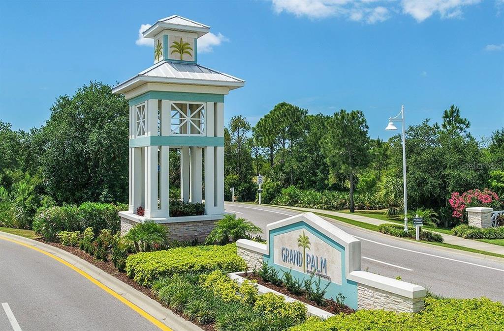 A tall, white, teal-accented monument sign marks the entrance to the Grand Palm community — 12630 HARNEY STREET, VENICE, FL