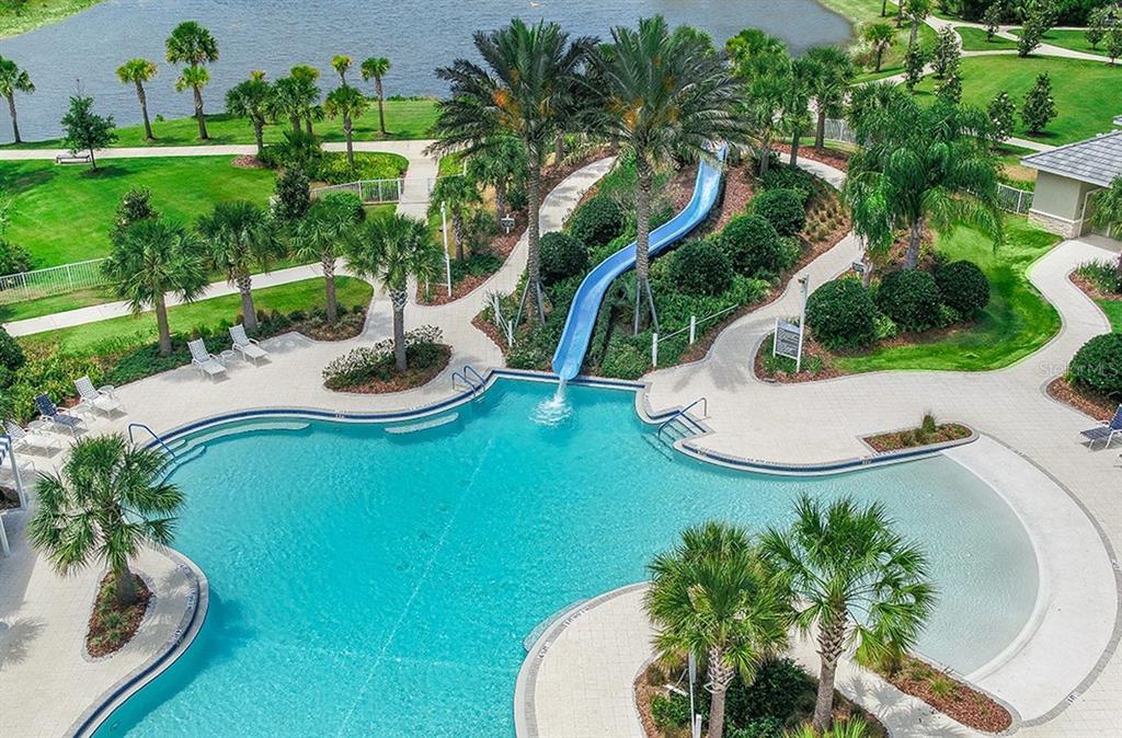 An aerial view of a swimming pool with a blue slide, palm trees, and landscaping — 12630 HARNEY STREET, VENICE, FL